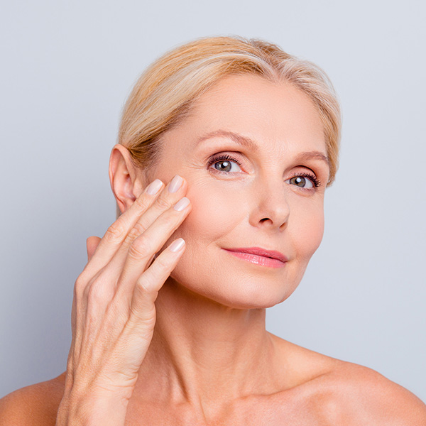 older woman touching her face